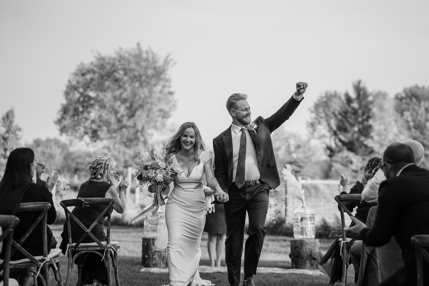 Happy Bride and groom go down the aisle together while groom fist pumps the air